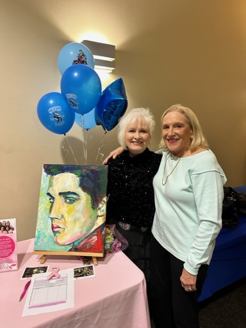 Ladies standing next to Elvis painting 