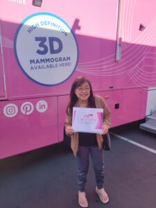 Women smiling with mammogram certificate in front of maddy