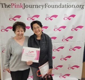 Two women smiling in front of pink journey backdrop