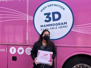 Women smiling with mammogram certificate in front of maddy